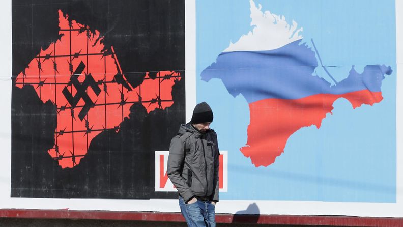 Paikallinen mies kävelee Krimin kansanäänestyksestä kertovan julisteen ohitse Sevastopolissa 13.3.2014.