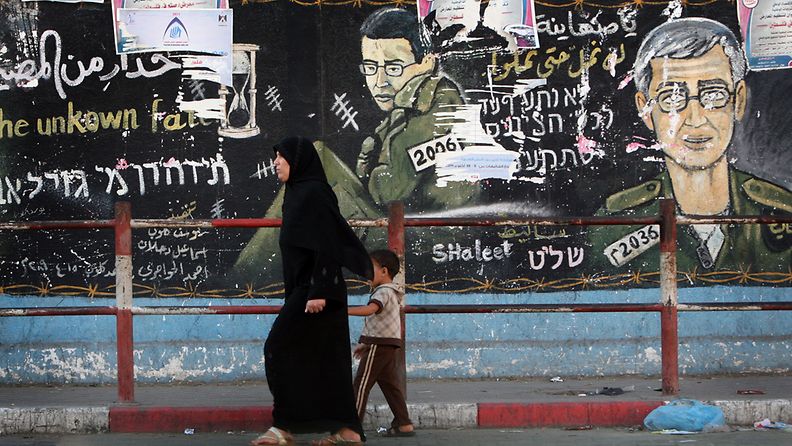Palestiinalaisnainen ohittaa seinämän, johon on piirretty siepatun Gilad Shalitin kuva, Gazassa. Kuva: EPA 