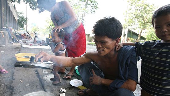 Filippiiniläinen perhe valmistaa riisiä kadulla. (EPA)
