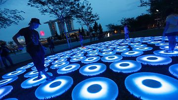 Akrobaatti Thomas Hauffen temppuili led-valon kanssa kävellessään Allas-nimisen valotaideteoksen päällä Singaporessa 19. maaliskuuta 2014.