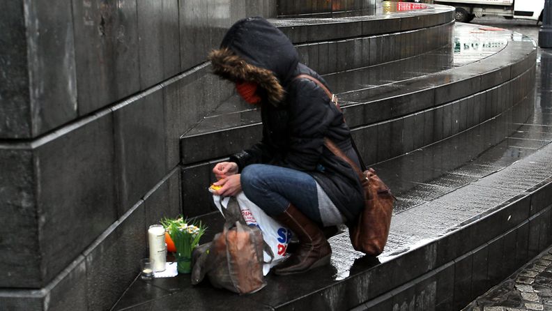 Nainen sytyttää kynttilän uhrien muistoksi Belgian Liegessä. Kuva: EPA