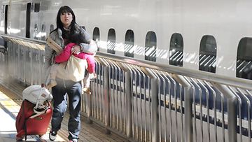 Nainen lähtee lapsensa kanssa pois Tokiosta 16.3.2011 Kuva:EPA