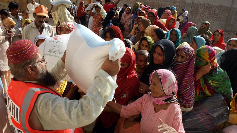 Women displaced from flooded areas line up to get relief goods at a temporary camp in Hyderabad, Pakistan, 08 October 2011.