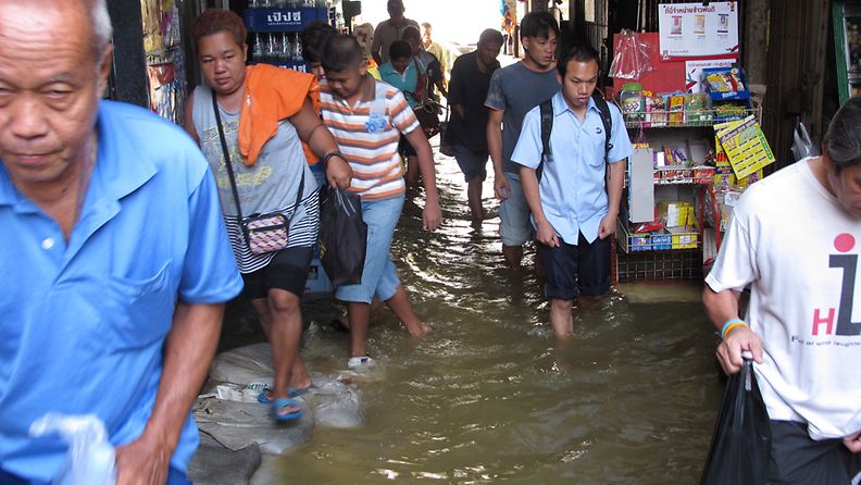 Thai residents walk through flooded streets as they come off boats on the Chao Phraya River in Bangkok, Thailand, 27 October 2011. 