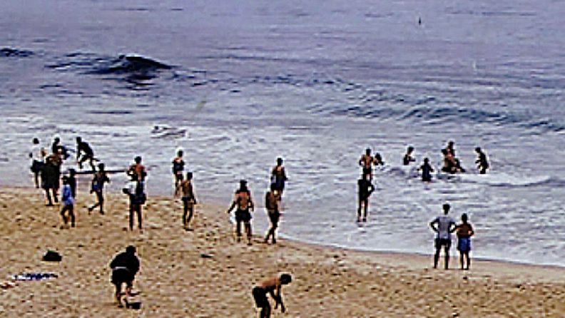Ihmiset kantavat erestä kahta hain hyökkäyksen uhreiksi joutunutta miestä Cottesloen rannalla Perthissä Australiassa 6.11.2000.