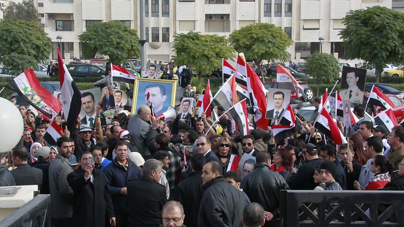 Tens of the Syrian regime's supporters shout pro-Syrian president slogans and wave Syrian flags in front of the Syrian Foreign Ministry while Syrian Foreign Minister holds a press conference in Damascus, Syria on 14 November 2011. 