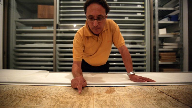 Dr. Adolfo Roitman, curator of the Dead Sea Scrolls and head of the Shrine of the Book points at the original Isaiah scroll found in Qumaran caves in the Judean Desert and dated around 120 BCE at the Israel Museum in Jerusalem, Israel, 26 September 2011. 