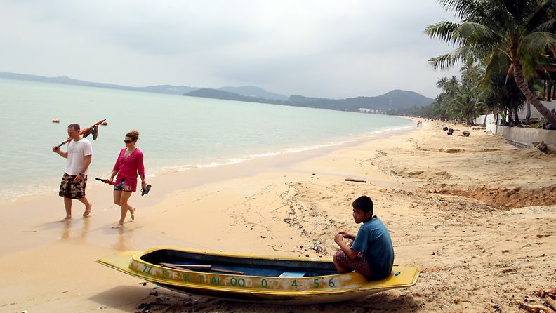 Turistit kävelevät rannalla suositulla Koh Samuin lomasaarella.