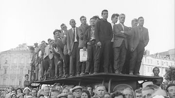 Rautatientori on täynnä yleisöä vastaanottamassa 30. kesäkuuta 1961 Suomeen sapuvaa neuvostoliittolaista kosmonautti Juri Gagarinia. Osa vastaanottajista on kiivennyt linja-autopysäkin katoksen päälle.  