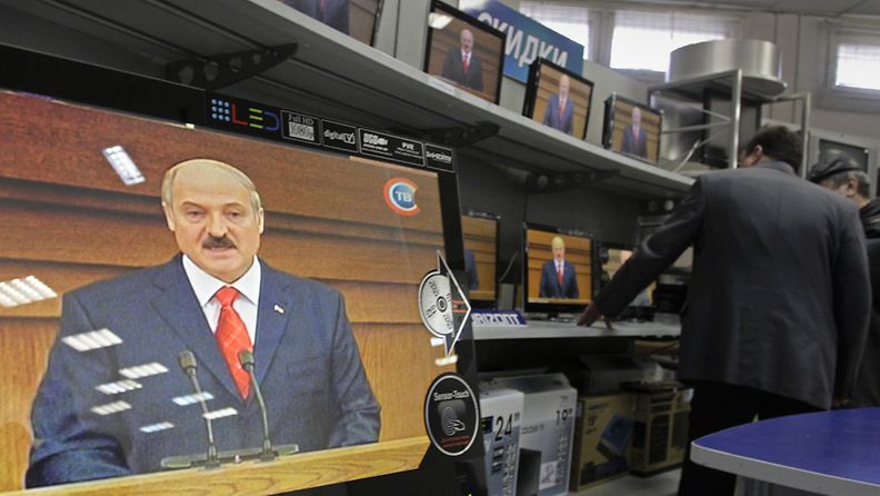 Valkovenäläiset valitsevat televisiota kaupassa, joka näyttää presidentti Lukashenkon puhetta jokaisessa ruudussa 21.4.2011. Kuva: EPA
