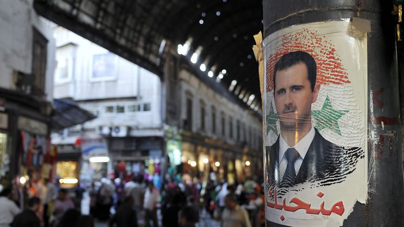 Ihmisiä Souq Al Hamidiya Basaarissa Damaskoksessa Syyriassa. Syyrian presidentin Bashar Al-Assadin kuva pylväässä. 2009