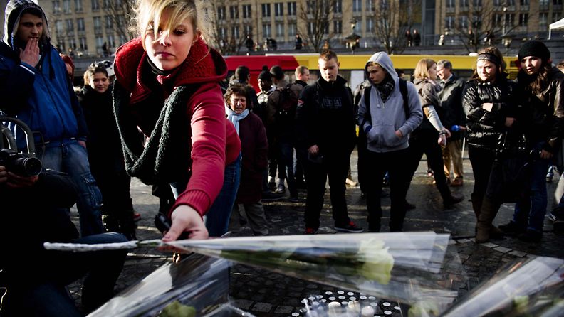 A woman places a white rose at the site of the tragedy in Place Saint-Lambert, Liege, Belgium, 14 December 2011. Three people were killed at the bus stop during the shooting and grenade attack in downtown Liege on 13 December, more than hundred people were injured. The gunman shot himself shortly after. A fourth victim was later found in a shed belonging to him.