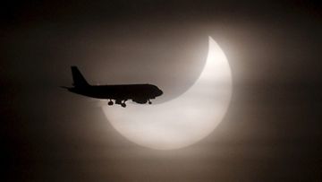 Lentokoneen silhuetti piirtyy auringonpimennyksen viereen Barcelonassa Espanjassa 4.1.2011. Kuva: EPA