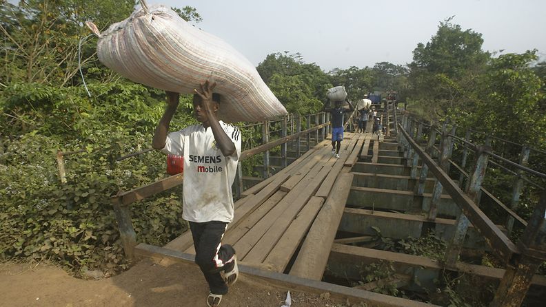 Mies kantaa kaakaopapusäkkiä Norsunluurannikolta Liberian rajan yli tammikuussa 2011.