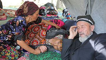 Nainen hoitaa vanhusta pakolaisleirillä Uzbekistanin rajalla 15.6.2010. Kuva: Epa