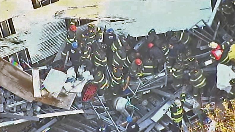 Pelastustyöntekijät etsivät rakennusmiehiä sortuneen talon raunioista. 