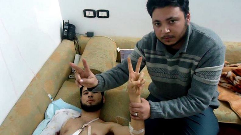 Syyrialaisaktivisti Khalid Abu Salah tapaamassa levottomuuksissa loukkaantunutta miestä Homsissa.