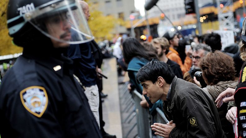 A man (R) prays while standing at the barricades around Zuccotti Park after the park was cleared of all tents and protestors in New York, New York, USA, 15 November 2011. 