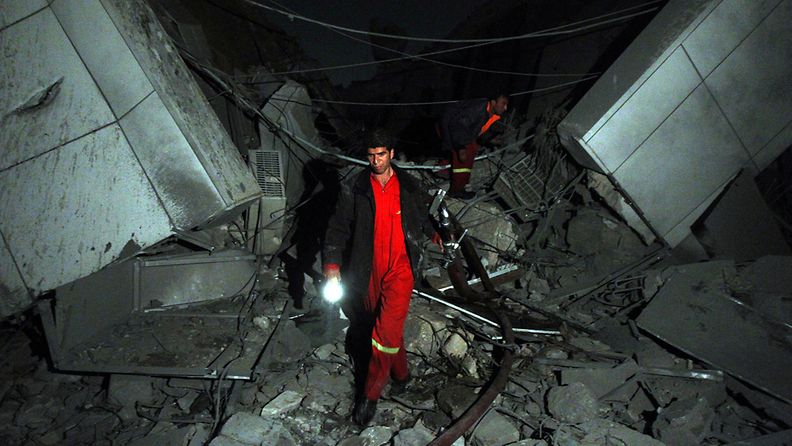 Nato iski Muammar Gaddafin päämajaan. Palomies kävelee tuhoutuneella alueella. EPA 