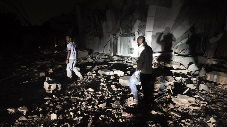 Nato iski Muammar Gaddafin päämajaan. Ihmiset kävelevät tuhoutuneen majan lähettyvillä. EPA 