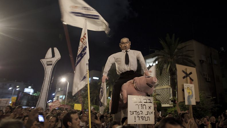 Demonstrators hold a puppet with the face of Israel's Prime Minister Benjamin Netanyahu sitting on a pig during a protest march against rising housing prices and social inequalities in Tel Aviv, on 06 August 2011.