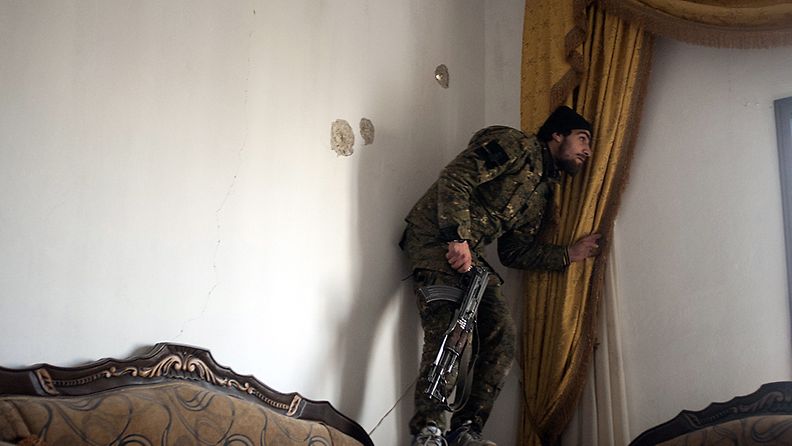 Aseistautunut mies piti vahtia aleppolaistalon olohuoneesta käsin Syyriassa 23. helmikuuta 2013.         