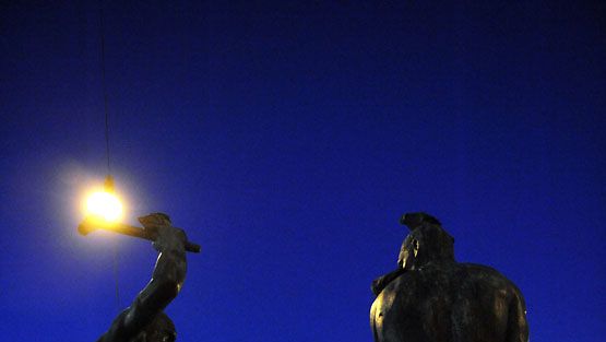 Kolmen Sepän patsas Helsingin keskustassa iltahämärässä. Lehtikuva
