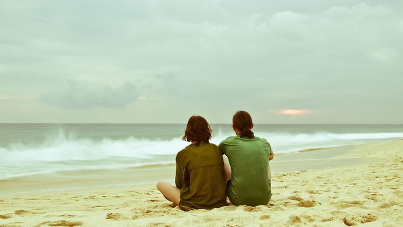 pari istuu rannalla
