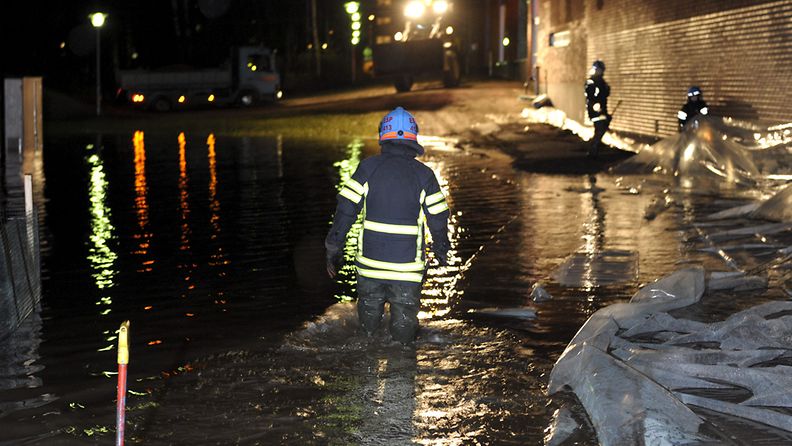 Palomiehet suojaamassa Kuninkaantien lukiota tulvalta Espoon keskuksessa maanantaina 19. joulukuuta 2011. 
