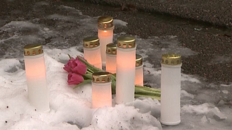 Murhatun äidin ja kahden pienen tyttären muistoksi oli tuotu kukkia ja kynttilöitä kotitalon eteen.