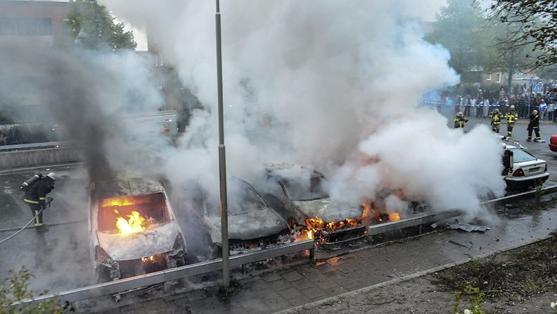Palomiehet sammuttavat mellakoijien jälkiä Tukholmassa 23.5.2012.