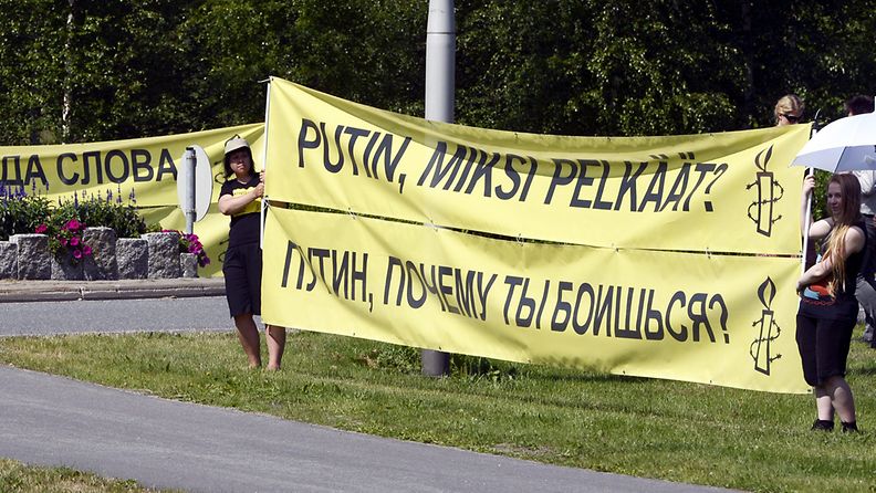 Mielenosoittajat odottavat Venäjän presidentti Vladimir Putinia Kultarantaan johtavan tien varrella Turussa 25. kesäkuuta 2013. 