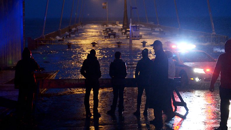 People look out on a flooded pier as the effects of Hurricane Sandy are felt in Rockaway Beach, New York, USA, 29 October 2012. Nearly 130,000 households were without power late 29 October in areas near Washington and New York as a result of Hurricane Sandy, regional authorities and power company officials said. New York Mayor Michael Bloomberg said there were an estimated 47,000 households without power in and around the city, while in the Washington and Baltimore, Maryland, areas, power companies reported about 80,000 households blacked out. EPA/JUSTIN LANE
