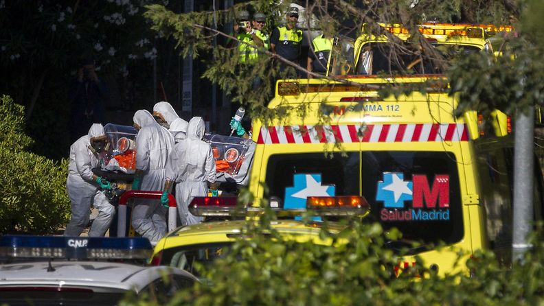 Madridissa suojapukuihin sonnustautunut hoitohenkilöstä siirtää Ebolaan sairastunutta pappia, joka lennätettiin Liberiasta Espanjaan 7. elokuuta 2014.
