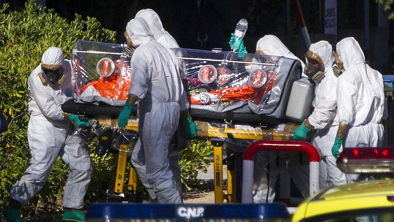 Madridissa suojapukuihin sonnustautunut hoitohenkilöstä siirtää Ebolaan sairastunutta pappia, joka lennätettiin Liberiasta Espanjaan 7. elokuuta 2014.