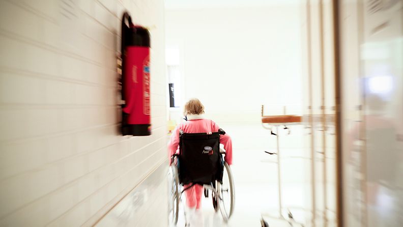 Potilas pyörätuolissa sairaalan käytävällä. 