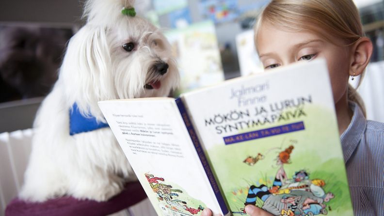 Tyttö lukee lukukoira Börjelle Sellon kirjastossa Espoossa.
