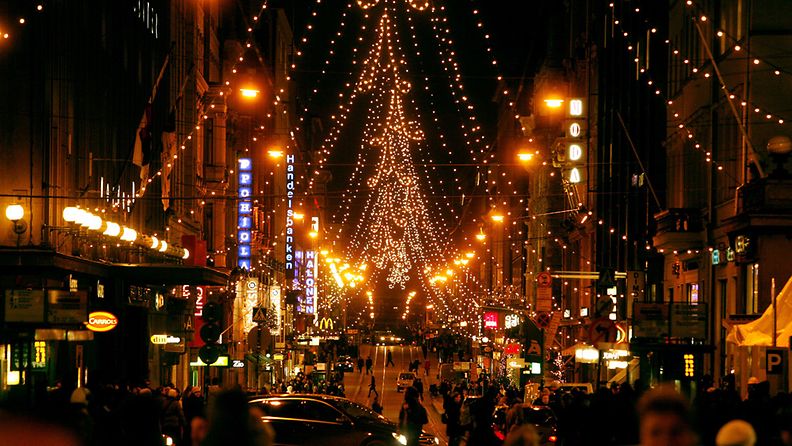 Ihmisiä jouluostoksilla Aleksanterinkadulla Helsingin keskustassa. ||| Christmas shoppers fill the illuminated Aleksanterinkatu street in downtown Helsinki.
