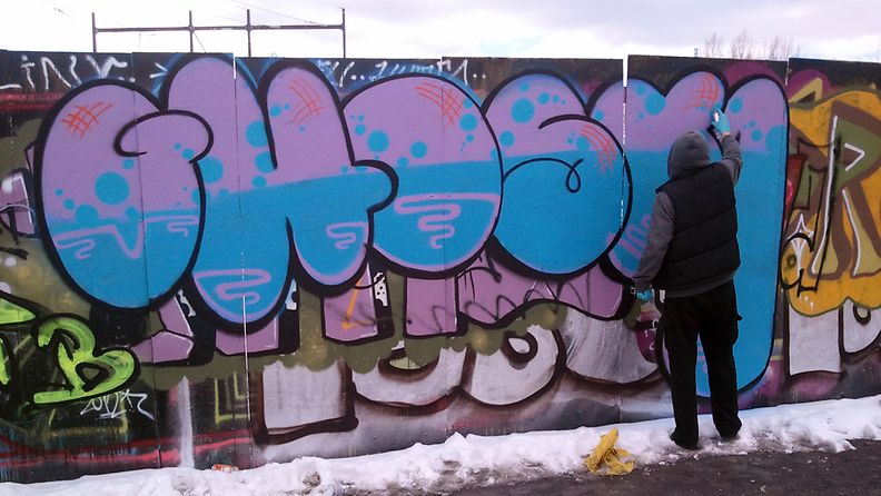 Graffititaiteilija Ghost työssään Helsingin Suvilahdessa.
