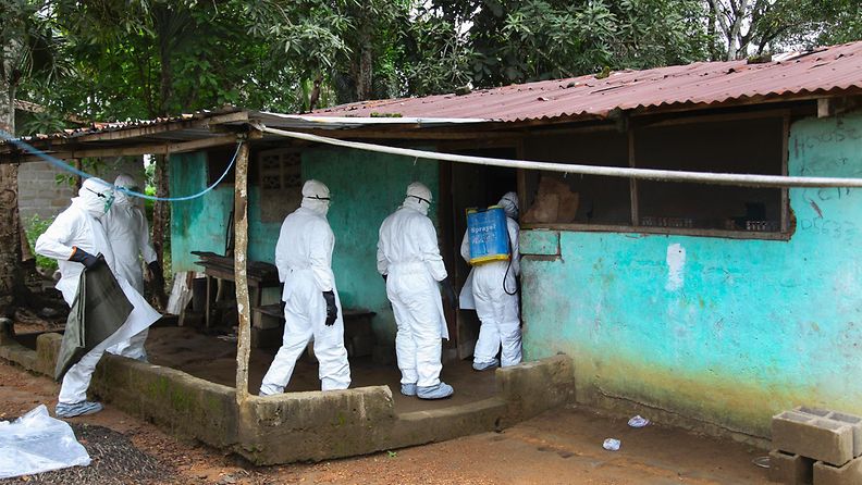 Liberialaiset sairaanhoitajat ovat menossa hakemaan Ebolaan menehtynyttä uhria tämän kotitalosta. 