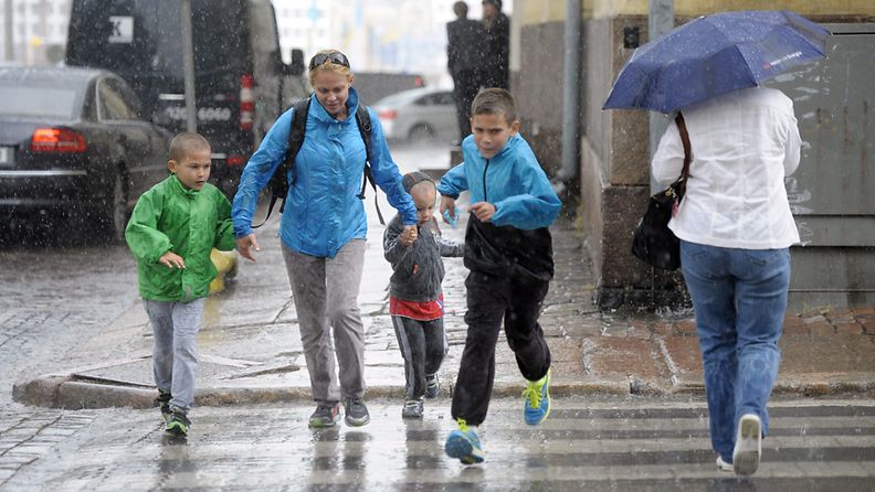 Ihmisiä juoksemassa suojatien yli sateisessa säässä Helsingissä kesäkuussa 2012.