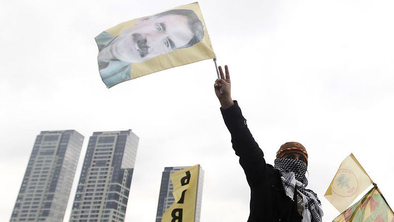 Kurdimies heiluttaa lippua, jossa Abdullah Öcalanin kuva.
