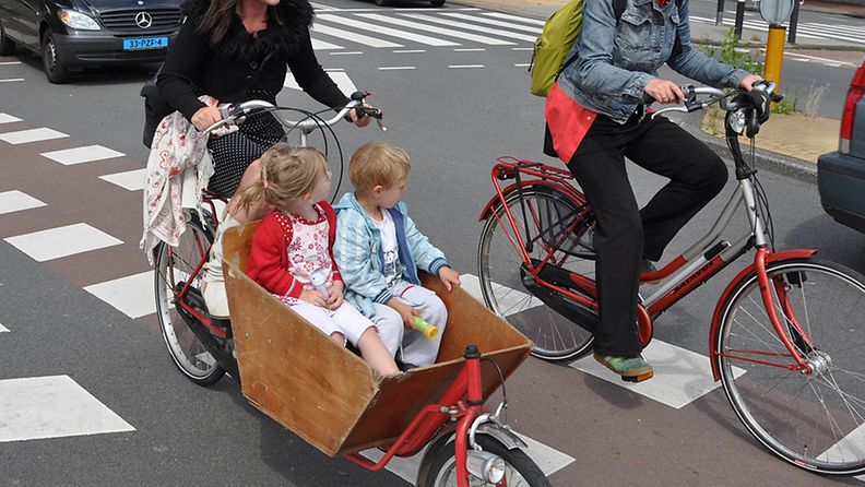 Naisella on kaksi lasta kyydissä, kun hän ajaa laatikkopyörällä Amsterdamissa 20. heinäkuuta 2011. 