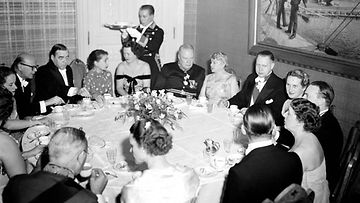 Linnan juhlat 6. joulukuuta 1953. Vasemmalla pääministeri Urho Kekkonen , Ralf Törngren ja rouva Sylvi Kekkonen. Pöydän ääressä myös Hollannin lähettiläs van der Vlugt, joka keskustelee rouva Alli Paasikiven kanssa sekä hänen vieressään oikealla Sakari Tuomioja (taulun alla).