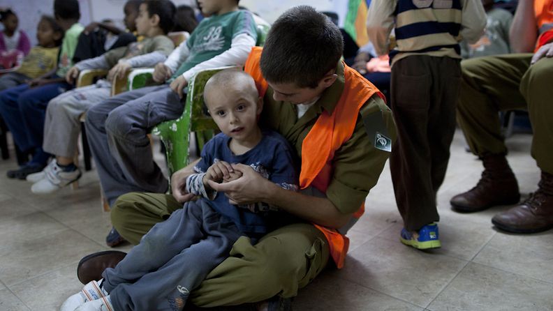 Kodinturvajoukkoihin kuuluva israelilaissotilas lohduttaa poikaa väestönsuojassa Ashkelonin kaupungissa.