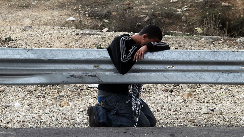 Palestiinalainen protestoija suojaa silmänsä kyynelkaasulta Howwaran tarkastusasemalla lähellä Nablusia.