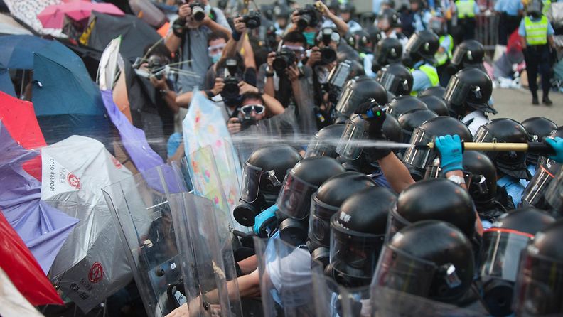 Hongkongin mielenosoittajat suojautuivat värikkäiden sateenvarjojen alle, kun poliisi yritti hajottaa sunnuntaina 28. syyskuuta 2014 mielenosoituksia kyynelkaasulla. 
