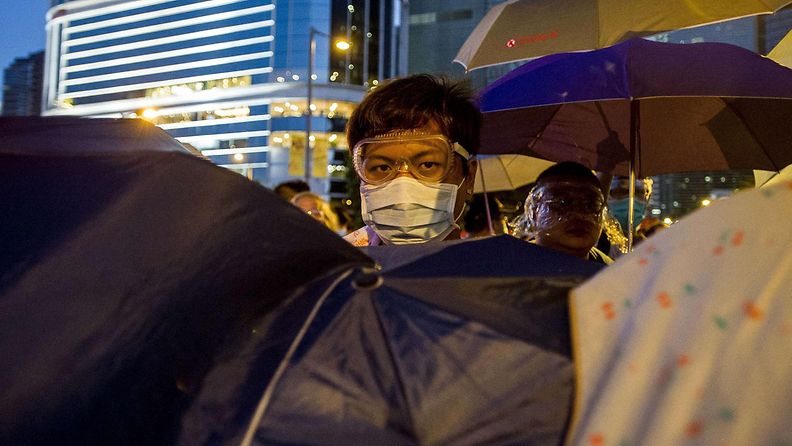 Hongkongin mielenosoittajat suojautuivat värikkäiden sateenvarjojen alle, kun poliisi yritti hajottaa mielenosoituksia kyynelkaasulla sunnuntaina 28. syyskuuta 2014.  