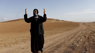 Kurdinainen näyttää surunsa seisoessaan Syyrian ja Turkin välisellä kukkulalla 26.10.2014. Kobanen kaupungin taistelut ovat hyvin lähellä.
