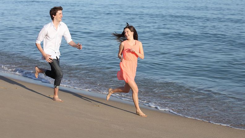 Pariskunta juoksee rannalla